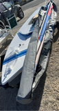 A white sailboat board with blue stripes and a gray sail cover on a dolly